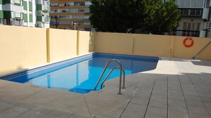 Ein Swimmingpool mit blau-weißen Fliesen, einer Metallleiter und einem Rettungsring an der Wand.