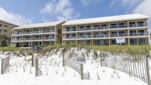 A beachfront hotel with multiple balconies and a warning sign about dunes.