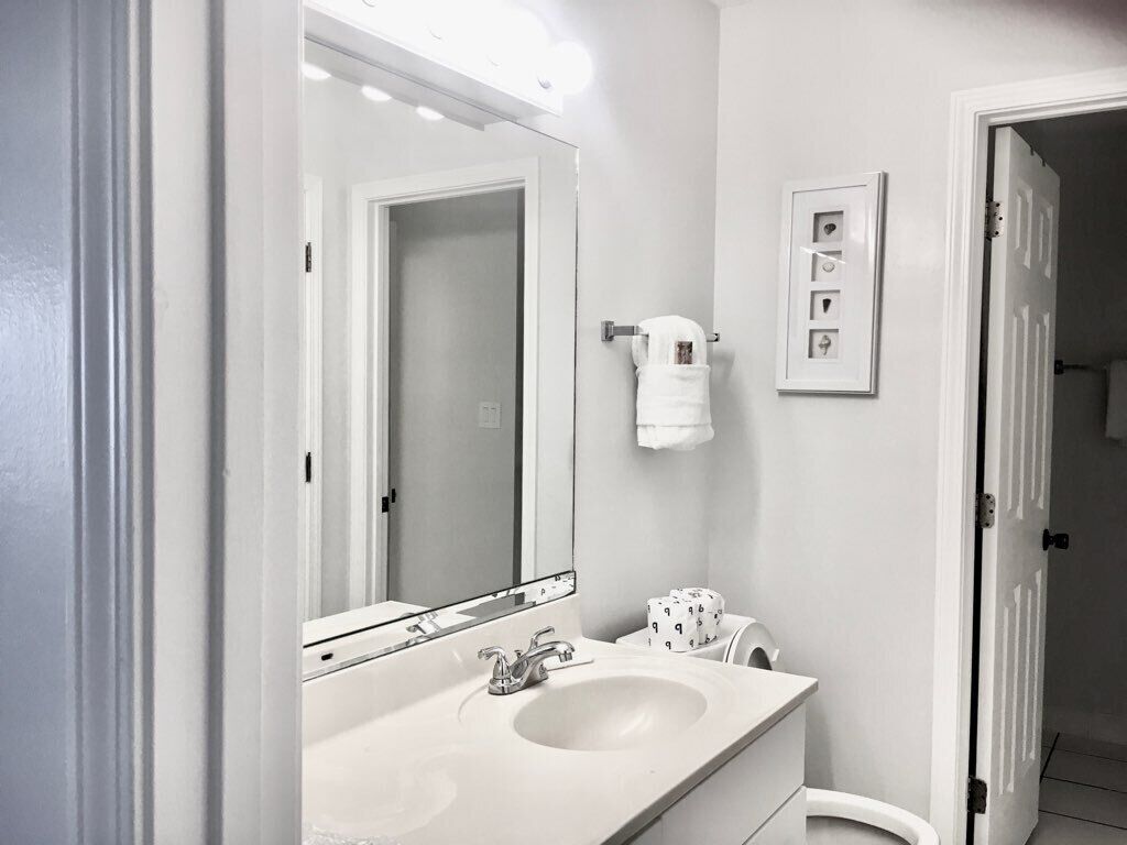 Une salle de bain avec deux lavabos, un grand miroir et un porte-serviettes.