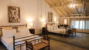 Un dormitorio con una cama grande, mesitas de noche, una silla y un espejo que refleja la habitación.