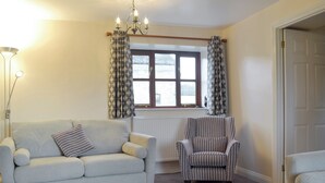 A living room with a sofa, armchair, and a radiator. - 3 bedroom accommodation in North Wootton, near Wells (North Wootton, near Wells)