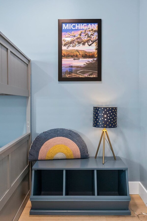 Una habitación con un cuadro enmarco de Michigan, una lámpara con motivos de estrella y un cojín colorido sobre un banco azul oscuro.