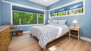 Ein Schlafzimmer mit einem Bett, zwei Nachttischen, einem Sessel und einer Kommode.