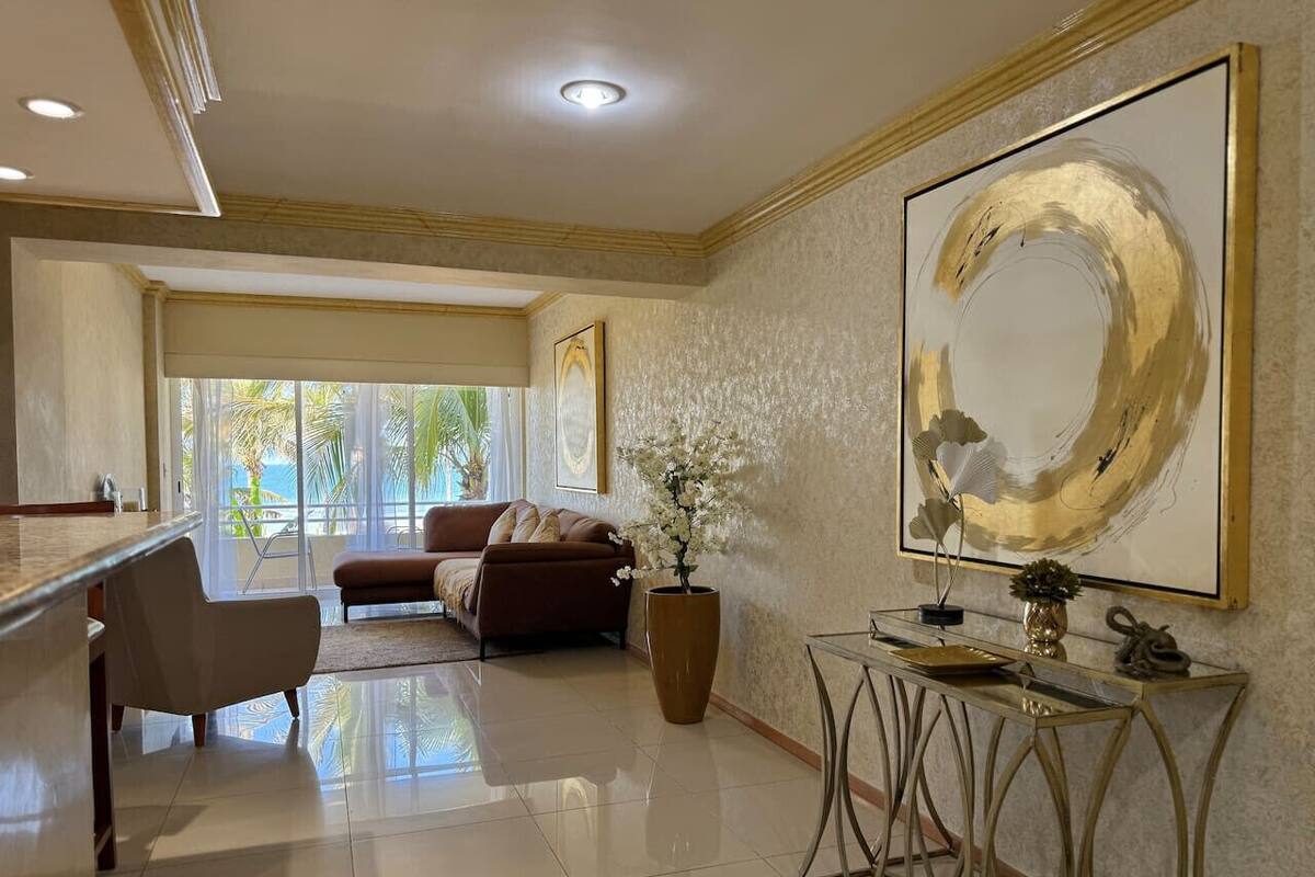 A spacious living area with a sofa, a coffee table, and a large abstract painting on the wall.