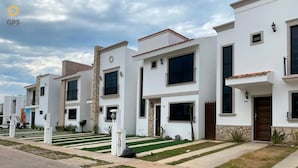 A row of modern, white two-story houses with stone accents, large windows, and a well-maintained lawn. - Azul Marino (Mazatlán)