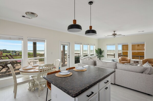 Una cocina moderna con una isla grande, muebles blancos y vistas al exterior.