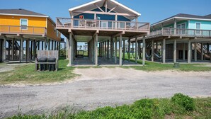 Une propriété située en bord de mer, composée de plusieurs constructions en bois soutenues par des piliers, et dotée de balcons et d’espaces de détente en plein air.