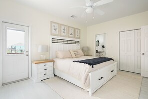 A bedroom with a bed, nightstands, a mirror, and a door. - Beachfront Views • Steps to the Sand • Dog Friendly • Sleeps 8 (Bolivar Peninsula)
