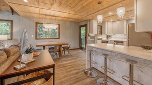 Una cocina moderna con gabinetes blancos, electrodomésticos de acero inoxidable y una barra con taburetes.