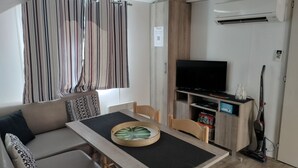 Ein modernes Wohnzimmer mit einer Couch, einem Esstisch, einem Fernseher und einem Staubsauger.