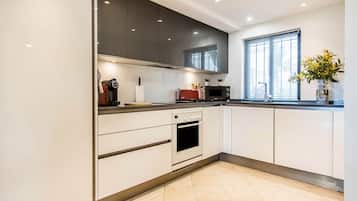 Une cuisine moderne avec des meubles blancs, un four encastré, un four à micro-ondes et une fenêtre offrant une belle vue.