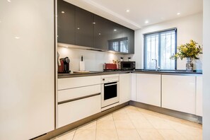 Una cocina moderna con armarios blancos, horno empotrado, microondas y ventana con vistas.