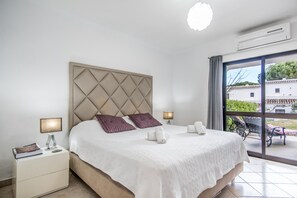 Ein Hotelzimmer mit einem großen Bett, zwei Nachttischlampen, einem Nachttisch und Blick ins Freie.