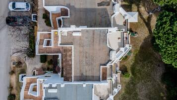An aerial view of a residential property with a central courtyard, multiple entry points, and a parking area with cars.