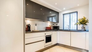 Una cocina moderna con armarios blancos, horno integrado, microondas y tostadora.
