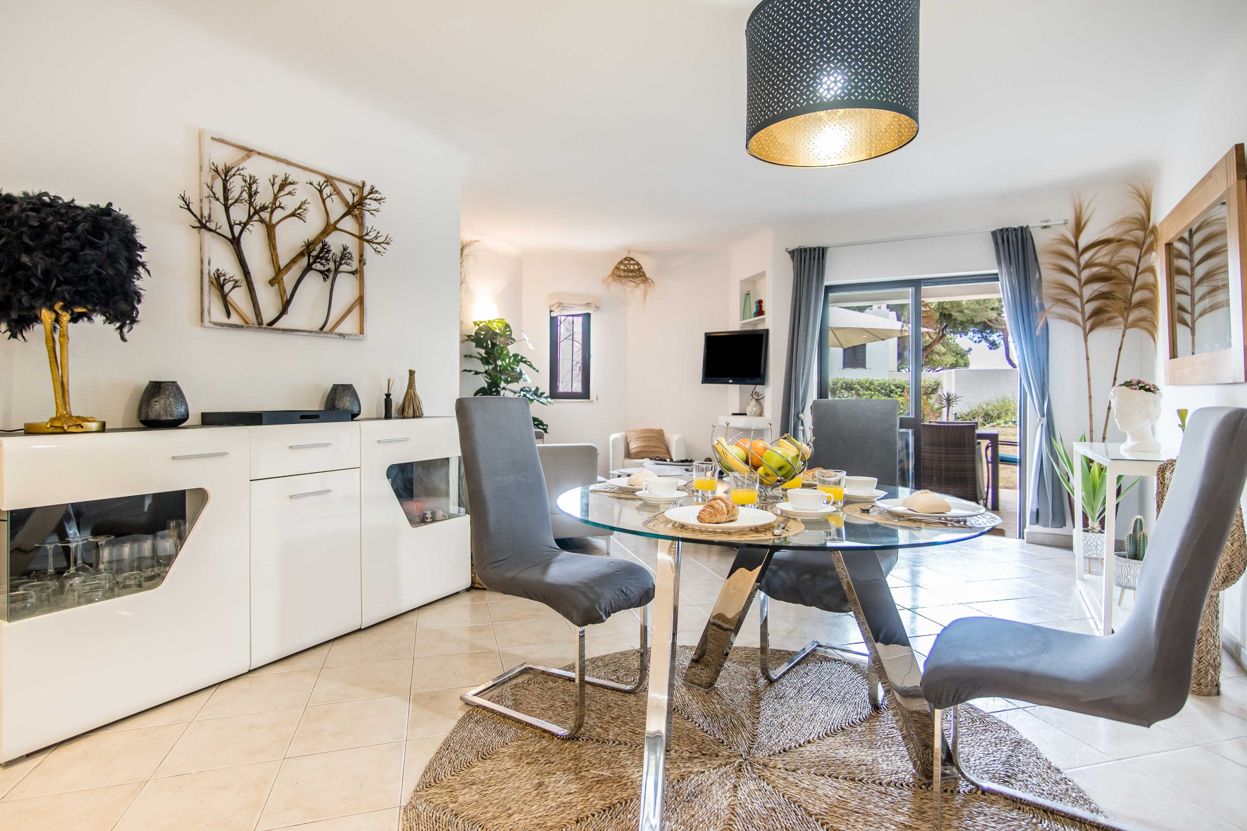 A modern kitchen with a dining area, a TV, and a view of the outdoors.
