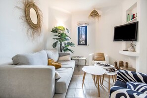 Una sala moderna con un sofá gris, una mesa de centro, un televisor y plantas decorativas.