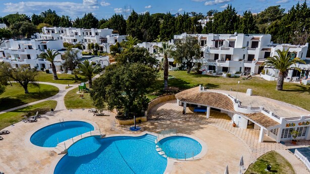 Un resort con varias piscinas, un club infantil y un césped bien cuidado.