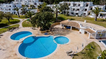 A resort with multiple swimming pools, a kids club, and a landscaped area with lounge chairs.