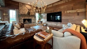 A cozy living room with a fireplace, leather sofa, and a television mounted on the wall. - ELLINGER COUNTRY FARMHOUSE  (Columbus)