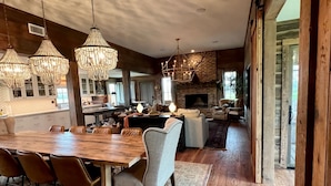 A spacious dining area with a large wooden table and chairs, a fireplace, and hanging crystal chandeliers. - ELLINGER COUNTRY FARMHOUSE  (Columbus)