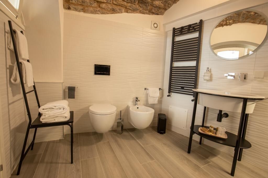 A modern bathroom with a toilet, bidet, and sink. There is a towel rack and a mirror.