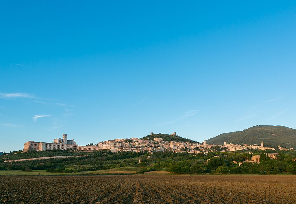 Un pueblo histórico con un edificio destacado en una colina, rodeado de campos y un cielo despejado.