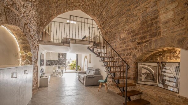 A spacious living area with a stone wall, a staircase, and a view to an upper level. - C' ERA UNA VOLTA  (Assisi)