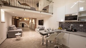 A modern kitchen with a dining area, featuring a staircase leading to an upper level, a built-in oven, and a tiled backsplash. - C' ERA UNA VOLTA  (Assisi)