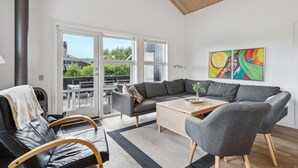 Uma sala de estar moderna com um sofá cinzento, duas poltronas, uma mesa de centro e uma lareira.