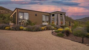 A modern house with a covered patio, surrounded by landscaped gardens and a gravel driveway. - Calistoga Wine Ranch Estate (Napa Valley)