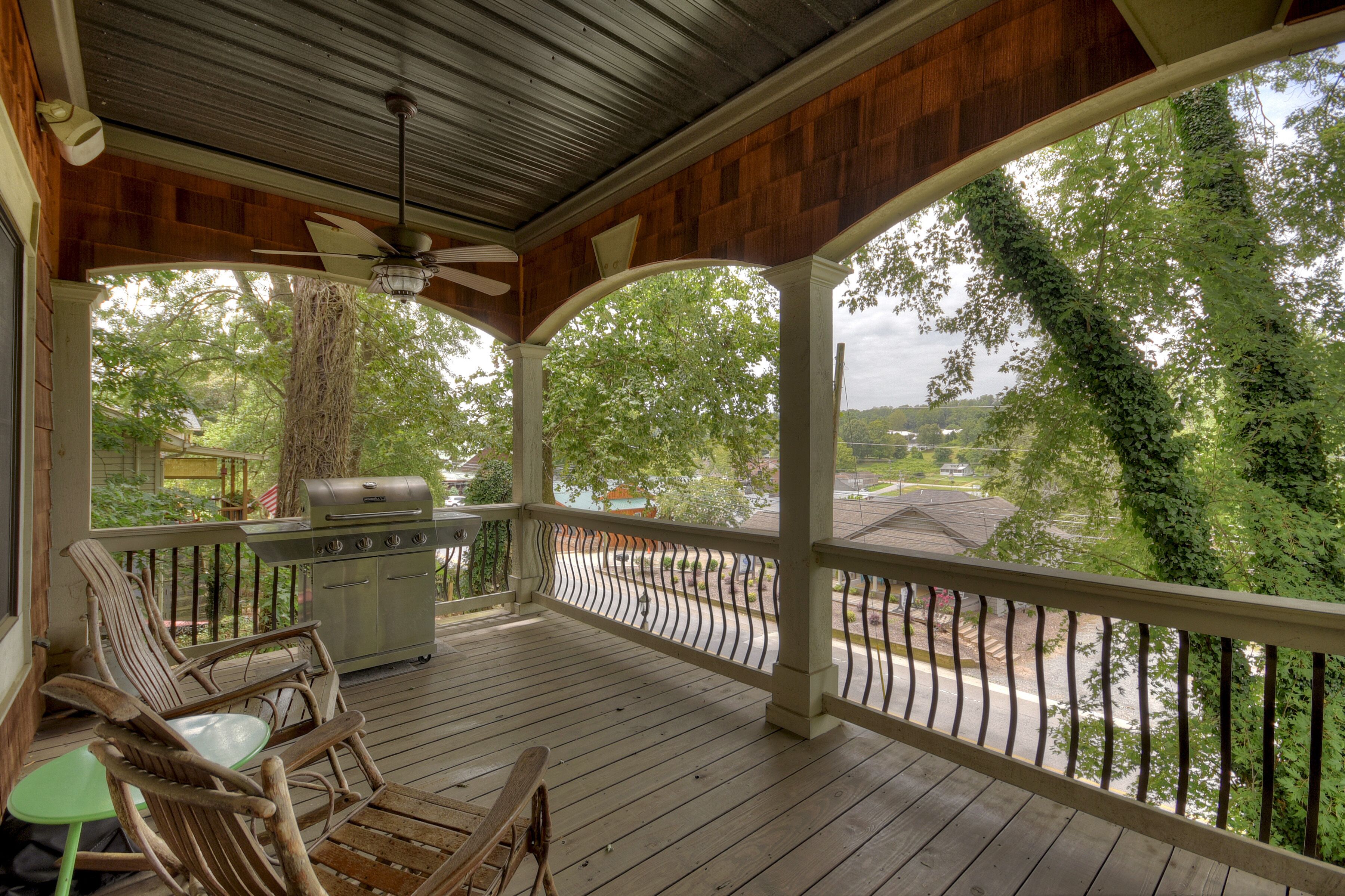 A covered porch with a grill, seating, and a view of the neighborhood.
