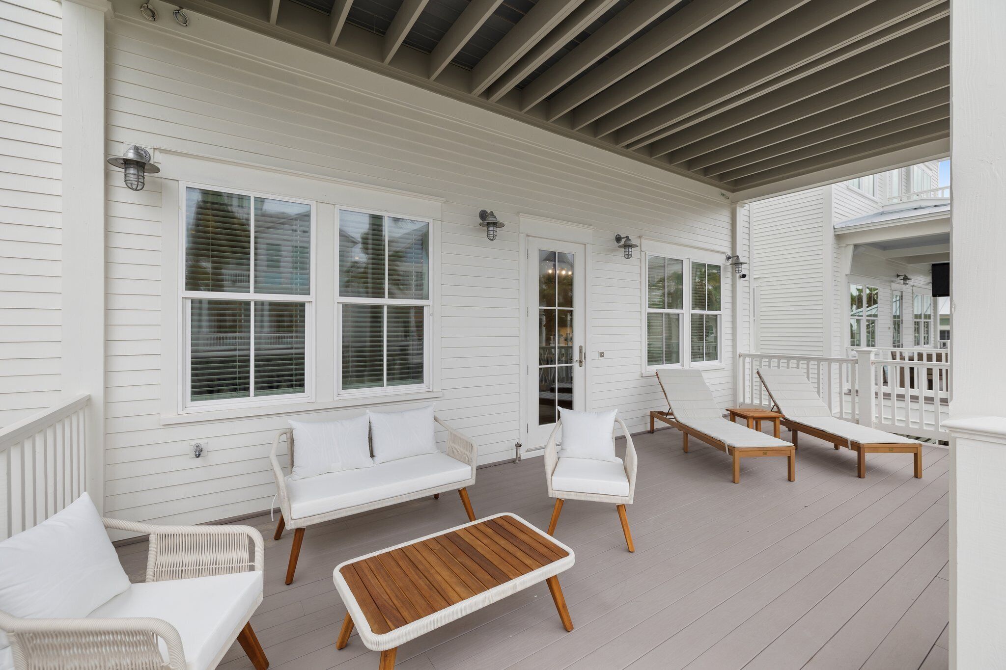 A covered porch with white railings, white furniture, and a wooden table.