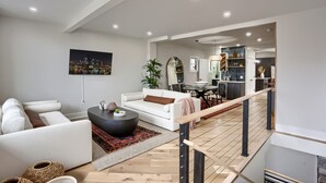 Un soggiorno moderno con un divano bianco, un tavolino da caffè nero e un quadro raffigurante un panorama urbano.