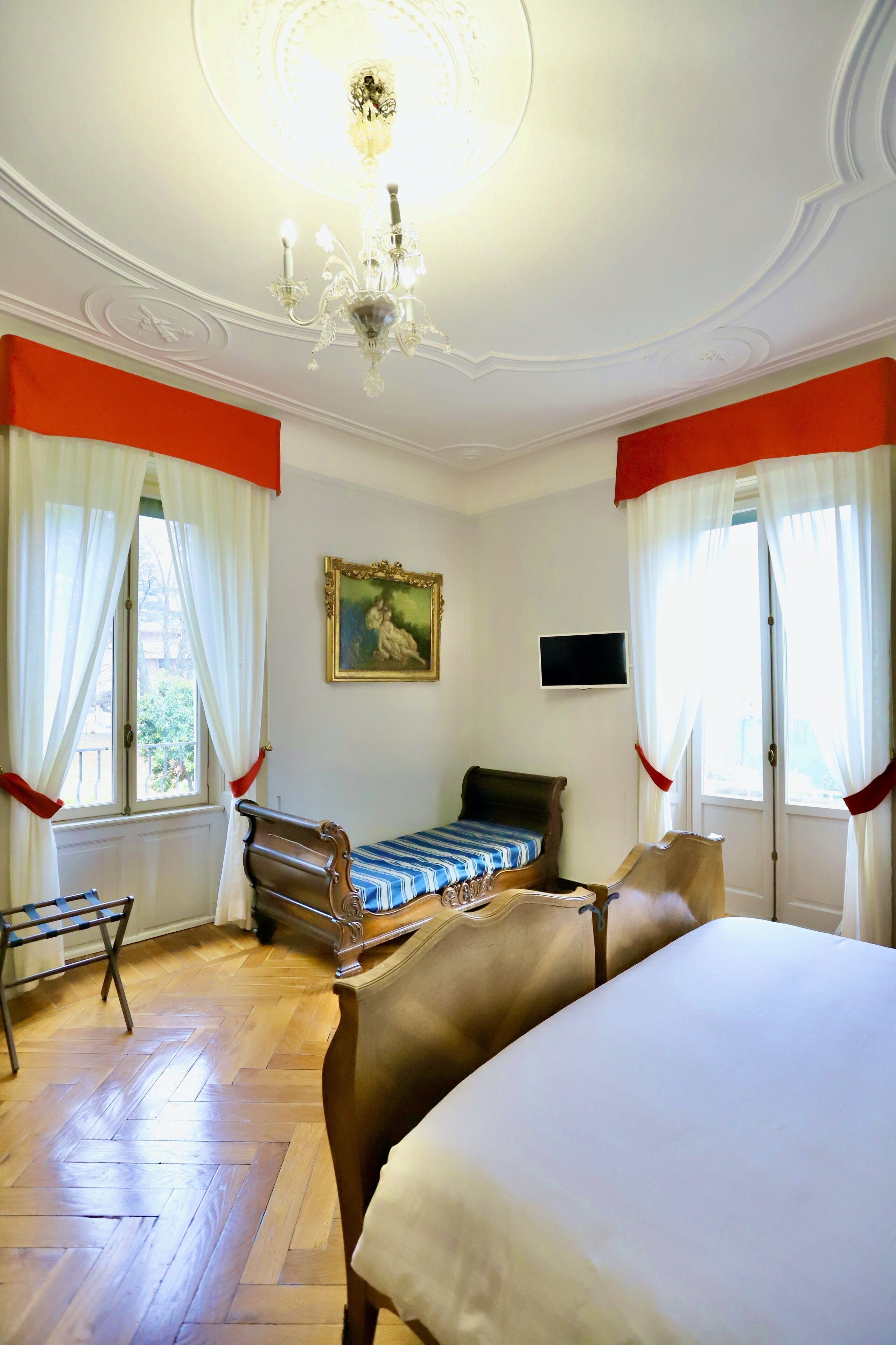 Un dormitorio con una cama grande, una cama más pequeña, una silla, un televisor y un cuadro en la pared.