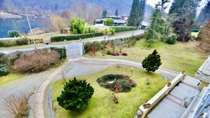A residential area with a well-maintained lawn, a paved driveway, and a stone pathway leading to a house. - La Villa Del Lago (Valganna)