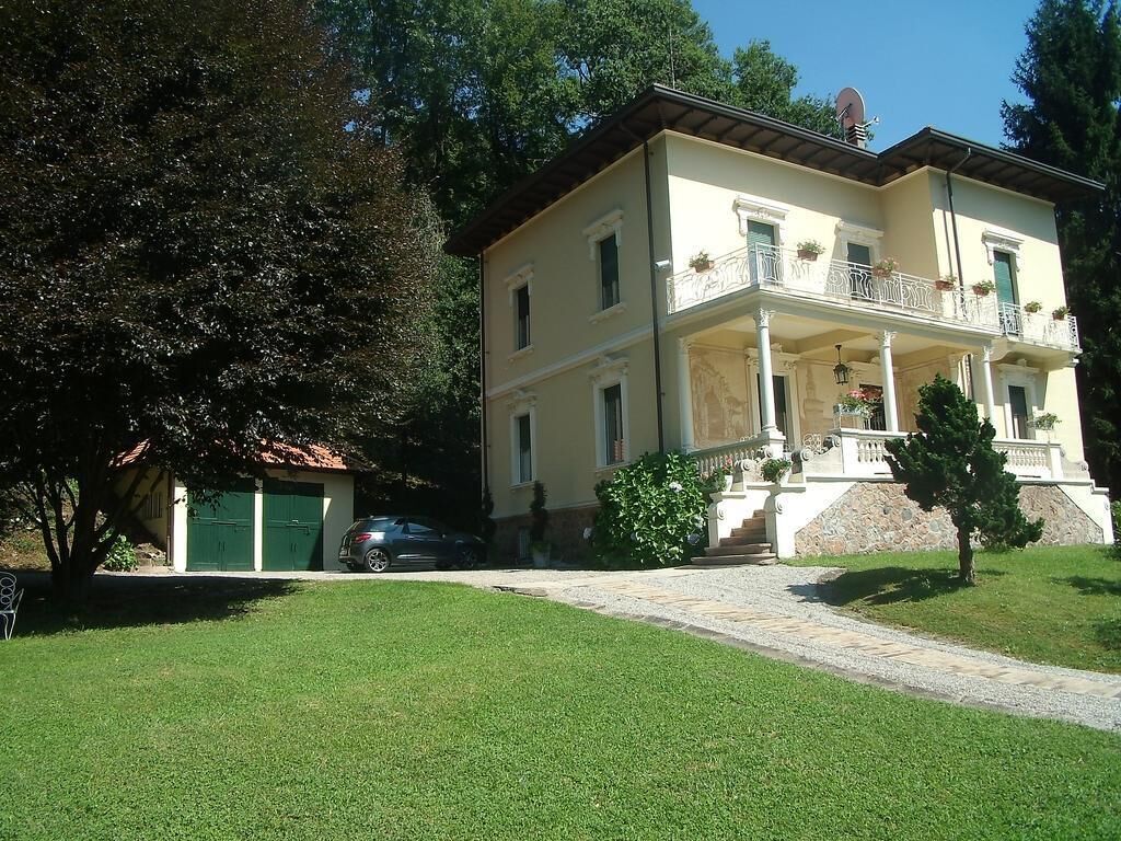 A two-story building with a balcony, a driveway, and a green lawn.