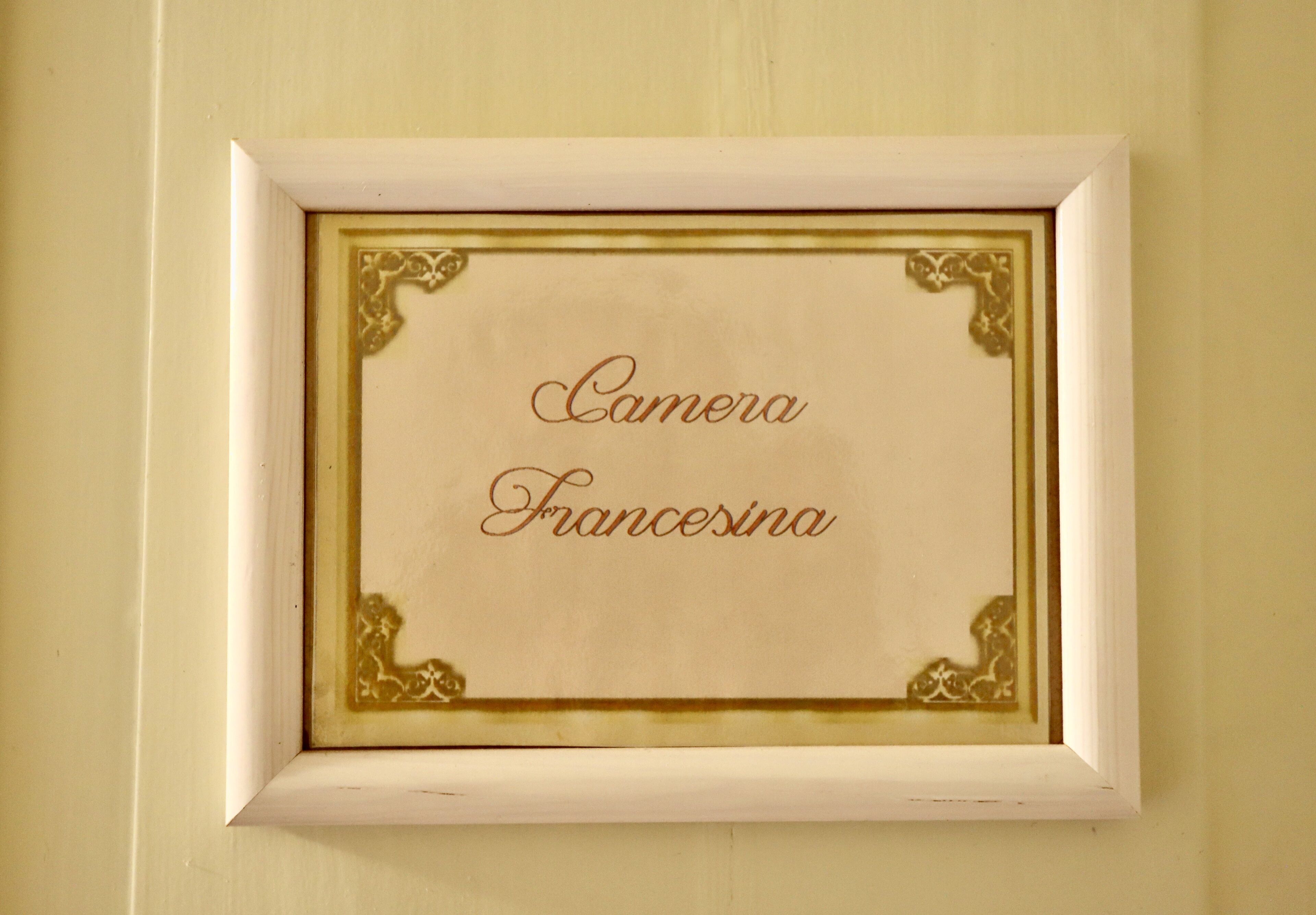 A framed sign with the text 'Camera Francesina' on a wall.