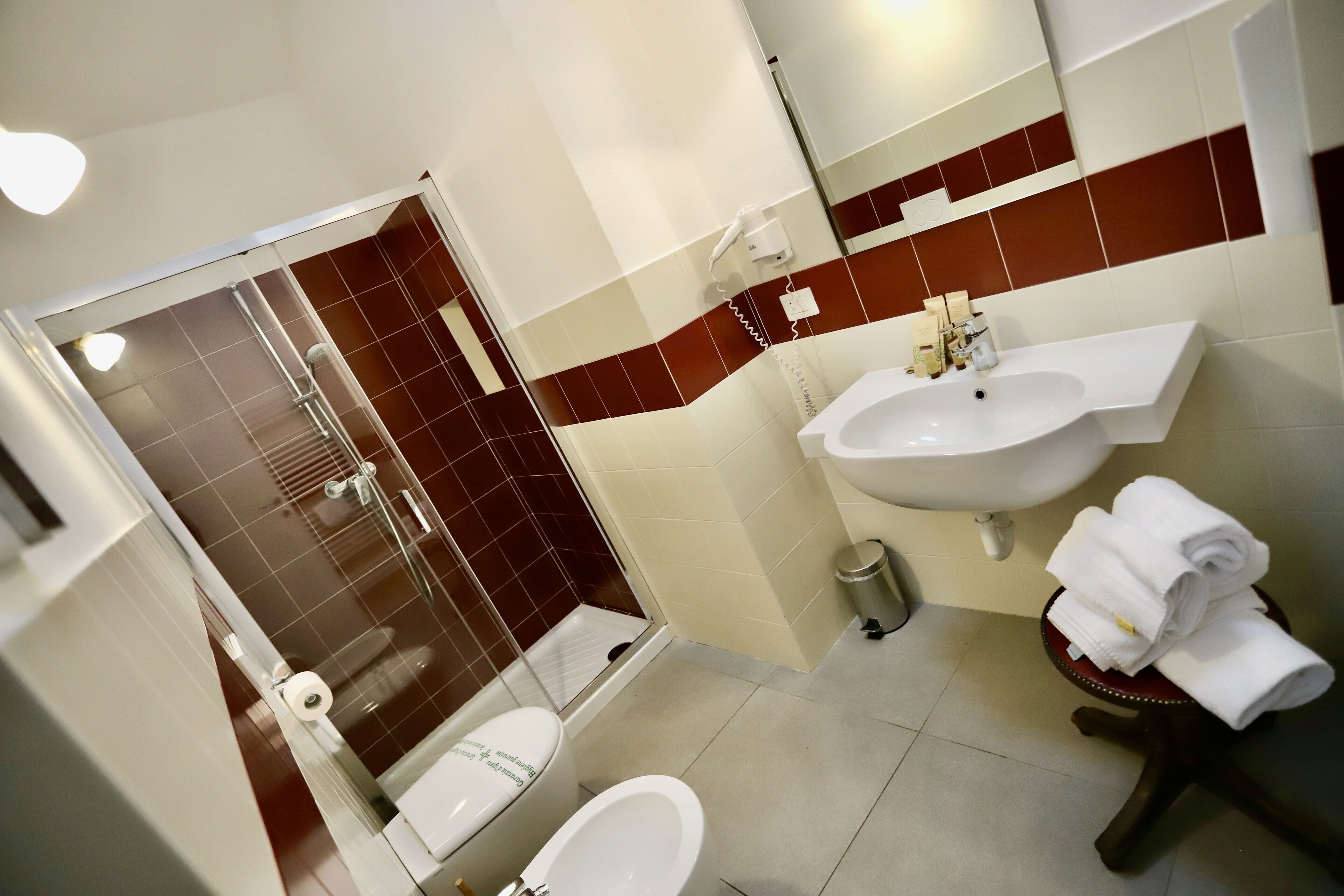 Un baño con ducha, inodoro, lavabo y una mesita con toallas.