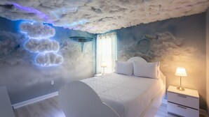 Ein Schlafzimmer mit einer Himmelhimmel-Decke, einem Bett, Nachttischen und einem Fenster mit Vorhängen.