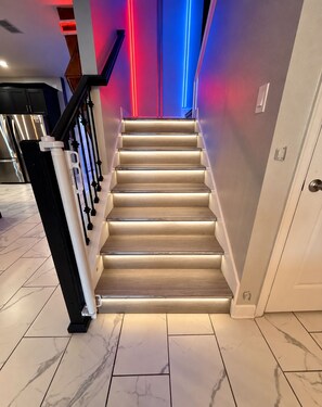 A staircase with a handrail and a light fixture on the wall.