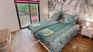 Un dormitorio con cama, mesita de noche, lámpara y vista al exterior a través de una puerta corredera.