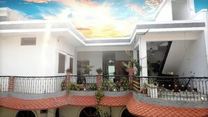 A two-story building with a red-tiled roof, a balcony with a metal railing, and a view of the sky. - Homestay Room with Wellness Programme city tour and guide (Khajuraho)