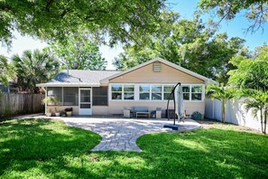 A single-story house with a covered patio area, a lawn, and a wooden fence.