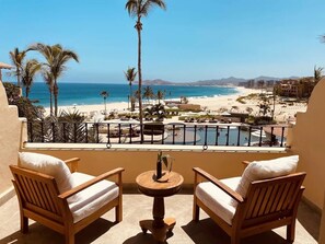 Relax on the balcony with a view of the resort's pool and ocean beyond.