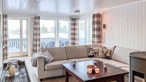 A cozy living room with a sofa, a coffee table, and a view of a snowy landscape through large windows. - Beautiful home in Noresund with WiFi (Noresund)