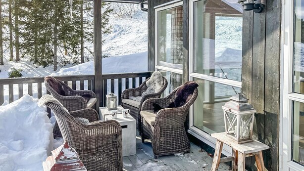 A covered outdoor seating area with wicker chairs and a table, overlooking a snowy landscape. - Beautiful home in Noresund with WiFi (Noresund)