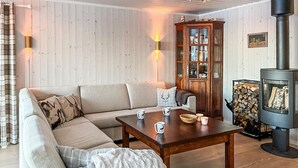 A cozy living room with a sectional sofa, a wooden coffee table, and a wood-burning stove. - Beautiful home in Noresund with WiFi (Noresund)