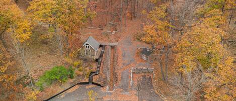 Une cabane avec un escalier en pierre menant à l’entrée, entourée d’un feuillage automnal.