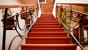 A staircase with red steps and metal railings, leading up to a brick wall.